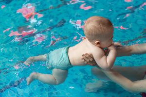 baby with mom learns to swim in the pool