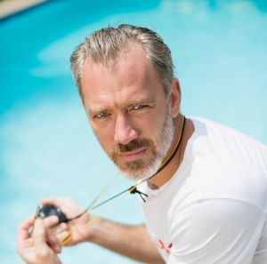 portrait swim coach holding stopwatch near poolside 1
